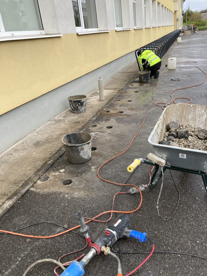 Teemantpuurimise seade ja voolikud asfaldil hoone seina ääres